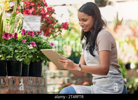 Sunshines her source. a nursery owner using her digital tablet. Stock Photo