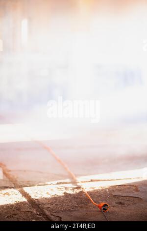 Electric power extension cable and cord on a concrete floor. Smoke in the background. Stock Photo