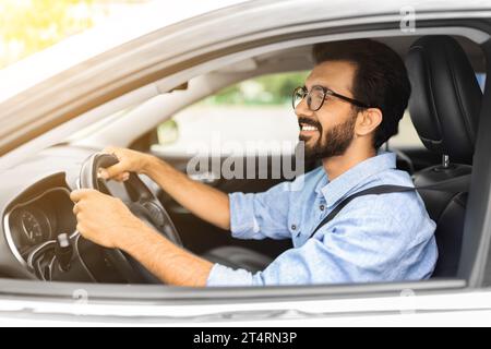 Cheerful eastern young man in casual manager driving white car Stock Photo