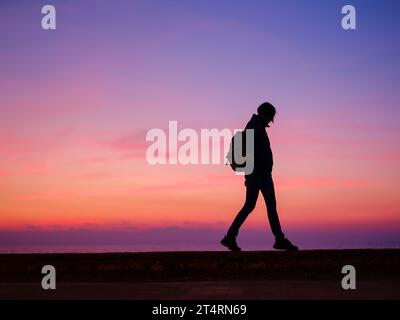 Woman tourist against colorful sunset sky. Travel, tourism concept. Active lifestyle. Stock Photo