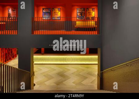 View down stairs to cloakroom with backlit yellow glass panel, with yellow seating in corridor above. Theater Zuidplein, Rotterdam, Rotterdam, Netherl Stock Photo