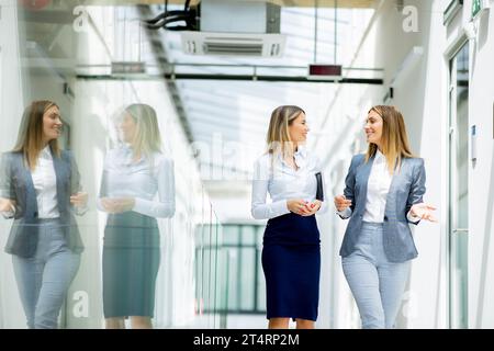 Two pretty young business women walking and discussing in the office hallway Stock Photo