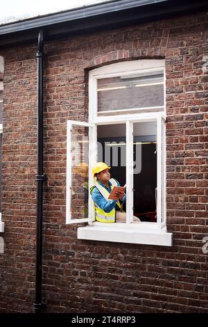 We can definitely expand this window. a engineer making notes while looking out the window of a construction site. Stock Photo