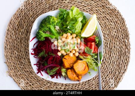 Vegan buddha bowl with chickpeas, broccoli, roasted sweet potatoes and salad shot from above. Stock Photo