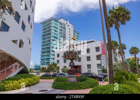 Tree-shaped statue adorned with locks, set against backdrop of charming buildings on Collins Avenue in Miami Beach, USA, on sunny day. Miami Beach. US Stock Photo
