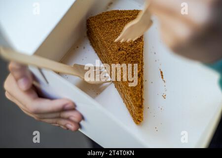 Close-up of a person holding an open box with a slice of honey cake Stock Photo