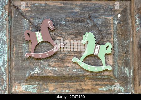 Christmas and New Year composition. Two Christmas toys (colorful wooden horses) on the old wooden surface with cracks and remnants of blue paint. Retr Stock Photo