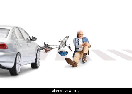 Mature man with a bicycle holding injured knee and sitting on the street in front of a car isolated on white background Stock Photo