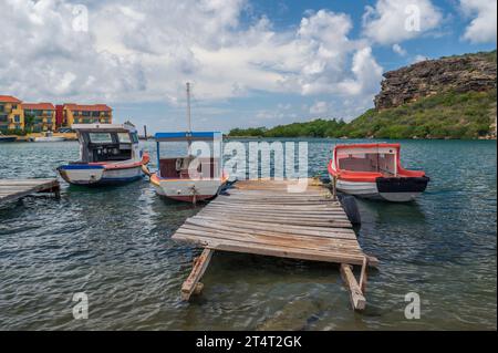 Small, colourful rowing boats, moored alongside a wooden jetty, on the Caribbean island of Curacao, in the Dutch Antilles Stock Photo
