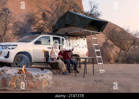 camping, tourism and travel concept - happy couple with smartphone taking selfie at tent camp Stock Photo