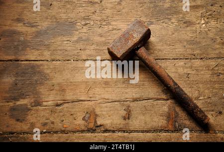 Very old rusty metal hammer on a shabby antique wooden floor. Simple background. Copy space Stock Photo