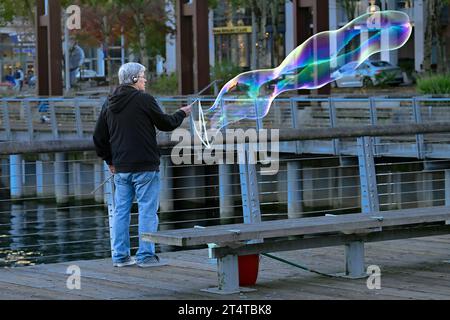 man making large soap bubbles, False Creek, Vancouver, British Columbia, Canada Stock Photo