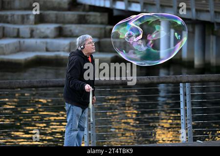 man blowing large soap bubble Stock Photo