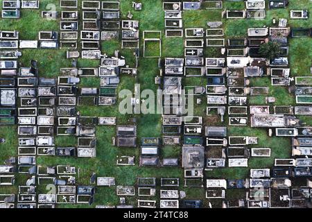 Aerial view directly above a packed inner city cemetery with rows of graves and tombstones in a grief or bereavement concept with copy space Stock Photo