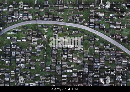 Aerial view directly above a packed inner city cemetery with rows of graves and tombstones in a grief or bereavement concept with copy space Stock Photo