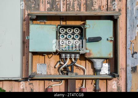 Old open fuse box on weathered wooden wall Stock Photo