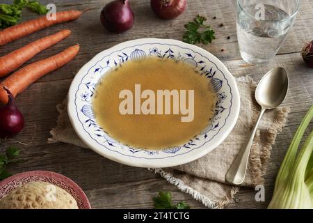 Chicken soup or bone broth in a vintage plate on a table Stock Photo
