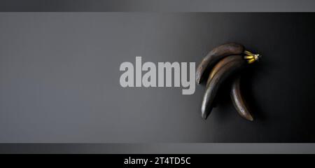 Bananas with a blackened peel on a dark background. Monochrome. Minimal artistic composition. Exclusive modern design poster. Copy space Stock Photo