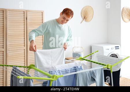 Young man hanging laundry on dryer at home Stock Photo