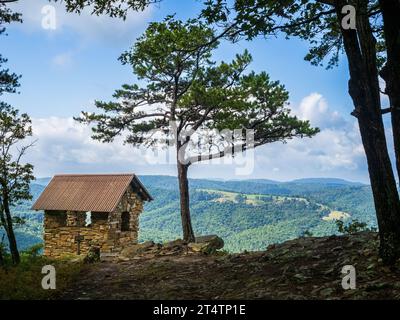 Nestled within the picturesque Cranny Crow Overlook in Lost River State Park, West Virginia, a charming small hut stands beside a resilient pine tree. Stock Photo