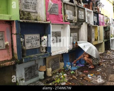 Caloocan, Philippines. 01st Nov, 2023. A woman lights a candle at her deceased relative's apartment tomb while holding an umbrella. People flock to Sangandaan Cemetery to observe UNDAS or All Saints Day in Caloocan City despite heavy downpours to visit their departed loved ones. The Philippine National Police (PNP) Caloocan were deployed outside the cemetery ensuring the order and safety of the public. (Photo by Josefiel Rivera/SOPA Images/Sipa USA) Credit: Sipa USA/Alamy Live News Stock Photo