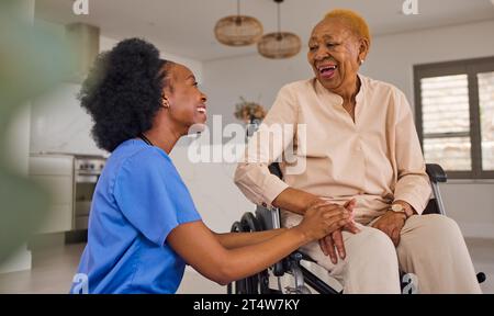 Black people, nurse and senior holding hands in wheelchair, elderly care and healthcare at home. Happy African female medical caregiver helping old Stock Photo