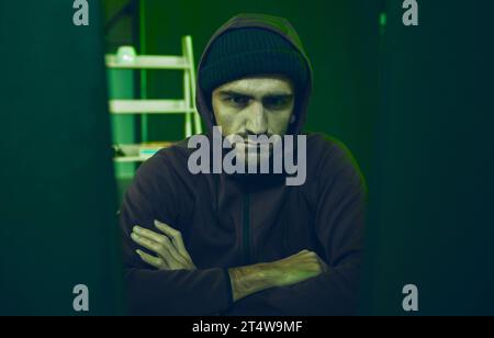 Cybersecurity, crime and portrait of hacker in neon basement with code, fraud and online scam. Software criminal, serious and professional hacker on Stock Photo