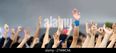 Many hands raised in a crowd of people Stock Photo