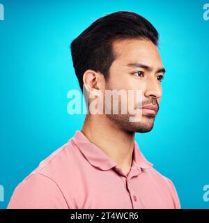 Thinking, serious and profile of Asian man in studio isolated on a blue background. Idea, side face and male person contemplating, lost in thoughts or Stock Photo