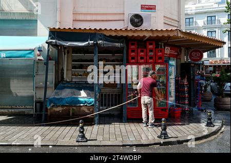 dedicated Istanbul store owner sprucing up the street outside his vibrant corner store, adorned with colorful fruits and refreshing beverages. Stock Photo