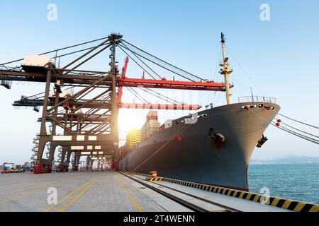Container cargo freight ship with working crane bridge in the port Stock Photo