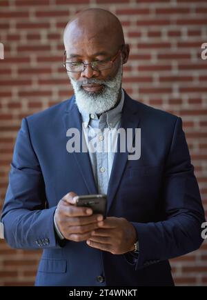 Startup, black man and manager with smartphone, online reading and connection for typing. Mature male, African American employee or leader search Stock Photo