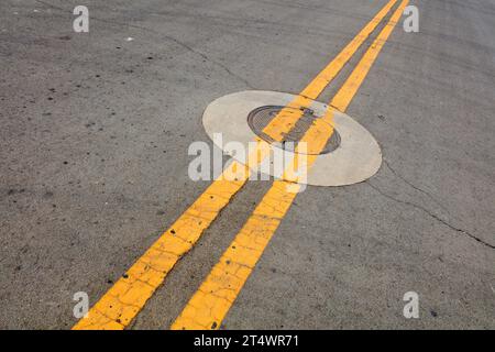 Yellow double solid line and circular manhole cover Stock Photo