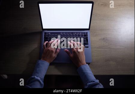 Person coding with laptop at night, hands typing on keyboard in the dark and internet website with white blank screen. IT student working at desk Stock Photo