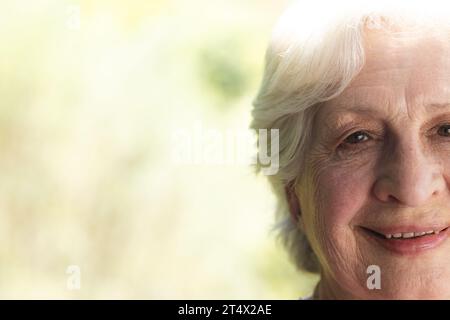 Half face of happy caucasian senior woman standing and smiling in sunny garden, copy space Stock Photo
