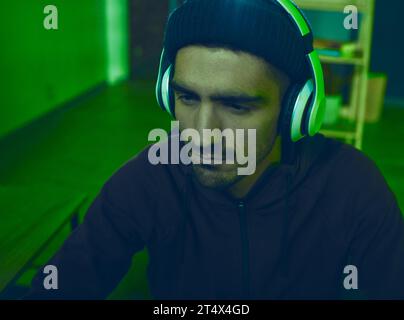 Headphones, man or hacker programming or coding for cybersecurity, online crime or cyber attack. Neon, big data or programmer reading software info Stock Photo