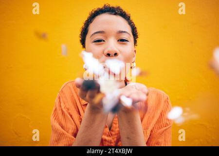 Flowers, petals and portrait of woman on orange background for natural beauty, skincare and romance. Blowing, happy and female person with floral Stock Photo