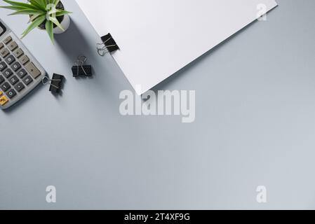 Top view of blank notebook, pen, calculator and green plant on grey office desk Stock Photo
