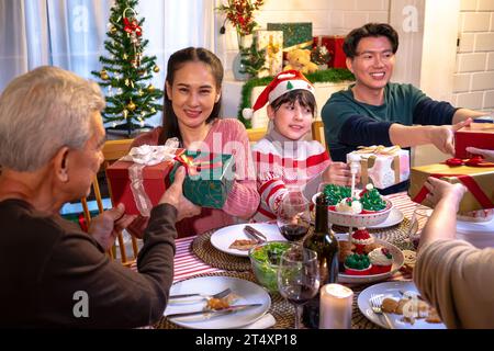 Happy people are celebrating on a table meal when christmas and new year at home. Cheerful elder , daughter ,son and child are eating dinner food with Stock Photo
