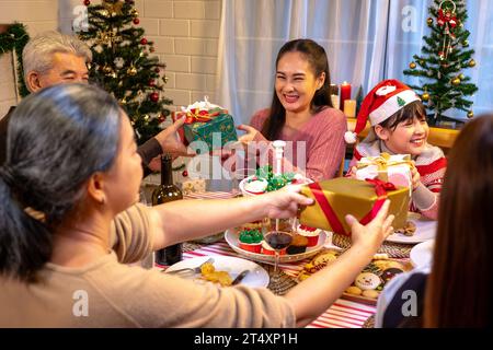 Happy people are celebrating on a table meal when christmas and new year at home. Cheerful elder , daughter ,son and child are eating dinner food with Stock Photo