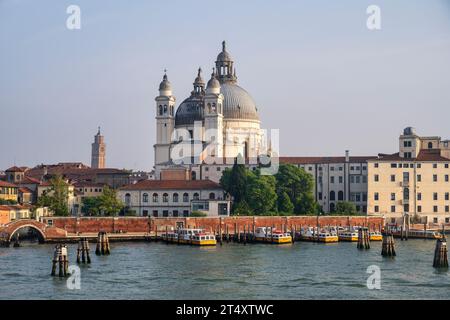 Basilica di Santa Maria della Salute viewed from Canale della Giudecca, with ferry boats by the Zattere promenade in Venice, Veneto Region, Italy Stock Photo