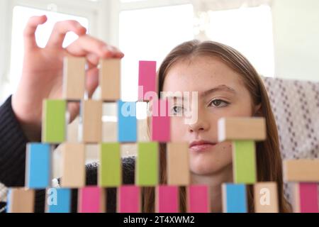Teenage girl constructing a wall of wooden blocks and building a tower Stock Photo