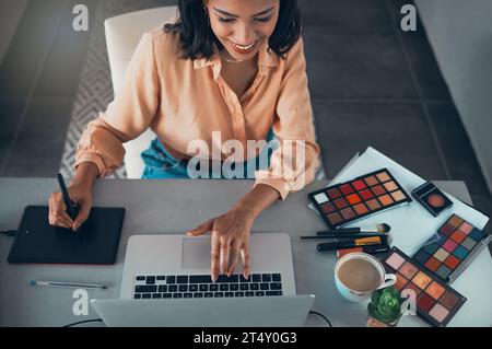 Graphic designer designing marketing advert for beauty products, makeup and cosmetics on laptop from above. Top view of smiling entrepreneur or Stock Photo
