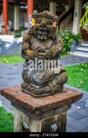 Park with tropical plants and traditional statues of the Hindu faith and for decoration. Tropical island life as a tourist on Bali, Indonesia Stock Photo