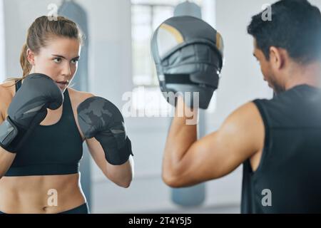 Boxing female boxer at gym with sports personal trainer practicing or training together for fight or match. Fitness and wellness coach teaching fit Stock Photo