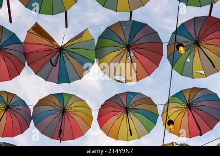 Lots of rainbow colored umbrellas on a street under  the blue sky, outdoor photography Stock Photo