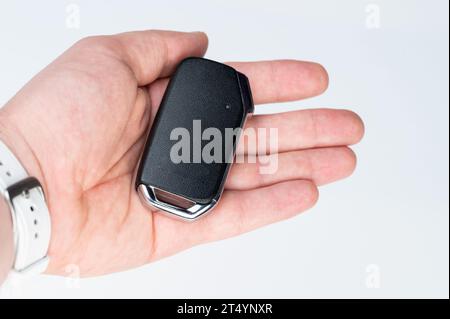 Modern car key in hand isolated on white studio background Stock Photo