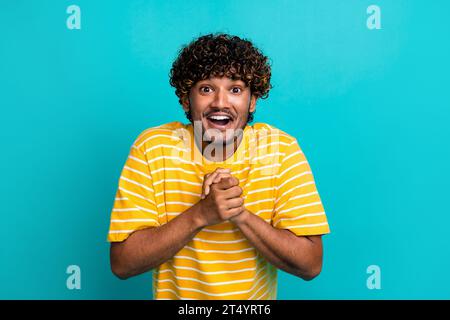 Photo portrait of handsome young guy hands excited grateful wear trendy striped yellow outfit isolated on aquamarine color background Stock Photo