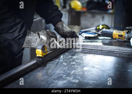 Man measuring off metal bar in industrial workshop. near Kocani Macedonia Stock Photo