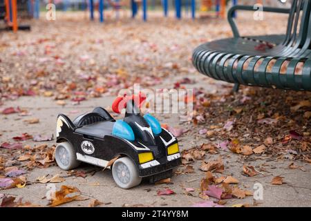 Toy Batmobile ride on car in a park in autumn, with leaves on the ground Stock Photo